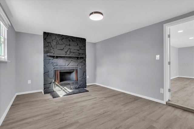 unfurnished living room featuring a fireplace and light hardwood / wood-style floors