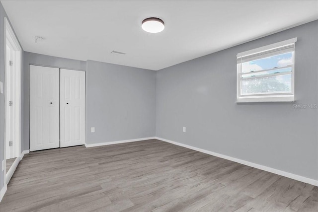 unfurnished bedroom with light hardwood / wood-style flooring and a closet