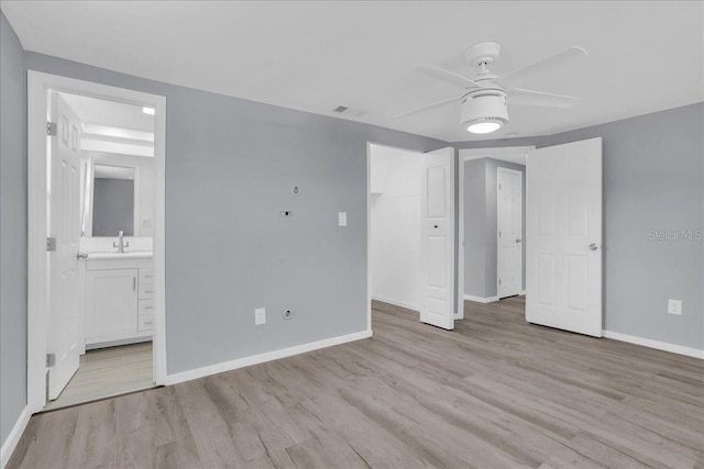 unfurnished bedroom with connected bathroom, sink, light hardwood / wood-style flooring, ceiling fan, and a closet