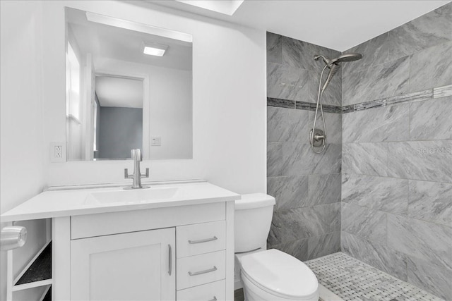 bathroom with vanity, a tile shower, and toilet