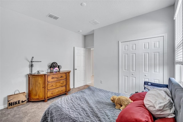 carpeted bedroom with a closet and a textured ceiling