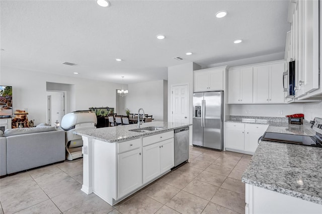 kitchen featuring an island with sink, sink, white cabinets, light stone counters, and stainless steel appliances