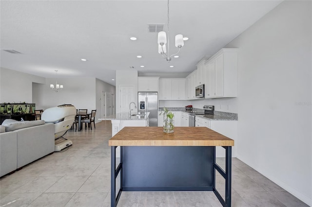 kitchen featuring white cabinetry, a kitchen breakfast bar, a notable chandelier, stainless steel appliances, and a center island with sink