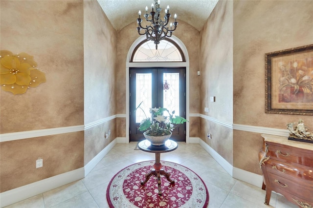 tiled foyer with vaulted ceiling, an inviting chandelier, and french doors