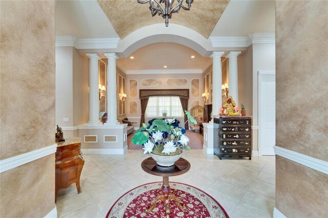 interior space featuring crown molding, lofted ceiling, light tile patterned flooring, and ornate columns