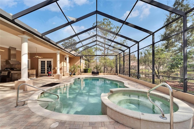 view of swimming pool with an outdoor kitchen, an in ground hot tub, ceiling fan, glass enclosure, and a patio area