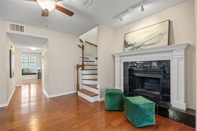 living room with a tile fireplace, wood-type flooring, and a textured ceiling