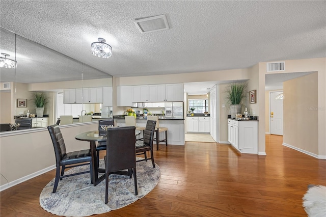 dining space with light hardwood / wood-style floors and a textured ceiling