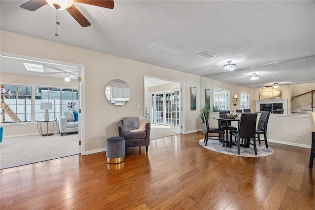 dining area featuring ceiling fan, wood-type flooring, a skylight, and a textured ceiling