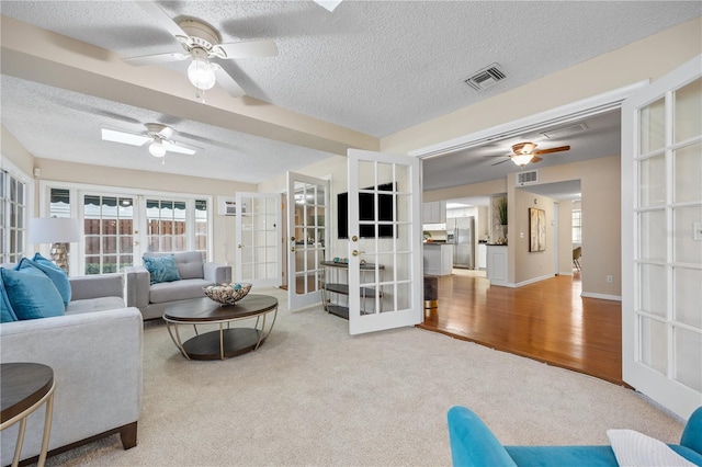 living room featuring french doors, ceiling fan, and a textured ceiling