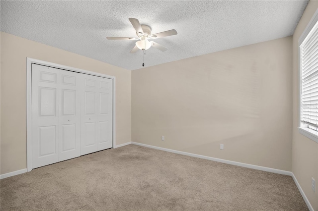 unfurnished bedroom with ceiling fan, light colored carpet, a textured ceiling, and a closet