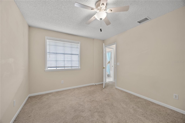 unfurnished room featuring ceiling fan, light colored carpet, and a textured ceiling