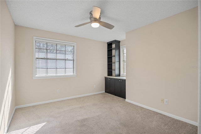 spare room with light carpet, ceiling fan, and a textured ceiling