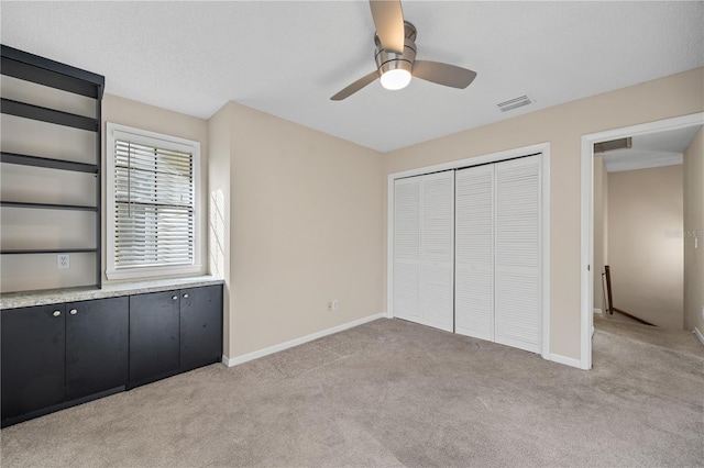 unfurnished bedroom featuring ceiling fan, light colored carpet, a closet, and a textured ceiling