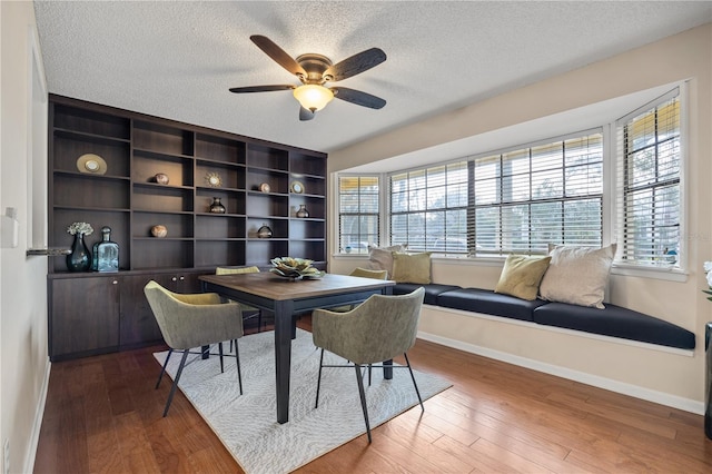 dining space with hardwood / wood-style flooring, ceiling fan, and a textured ceiling