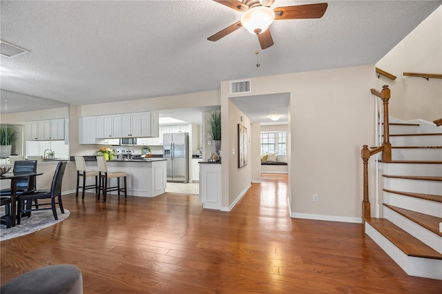 living room with hardwood / wood-style flooring, ceiling fan, and a textured ceiling