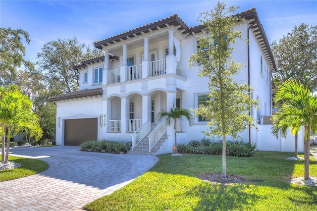 mediterranean / spanish house featuring a garage, a balcony, decorative driveway, a porch, and a front yard