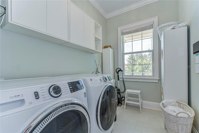 washroom featuring light tile patterned floors, baseboards, cabinet space, washing machine and clothes dryer, and crown molding