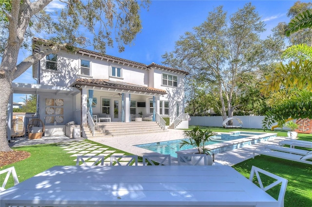 back of property featuring a fenced backyard, a tile roof, a lawn, a fenced in pool, and stucco siding