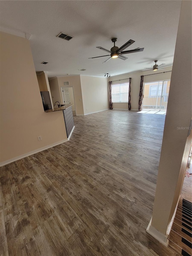 unfurnished living room featuring ceiling fan, wood-type flooring, and a textured ceiling