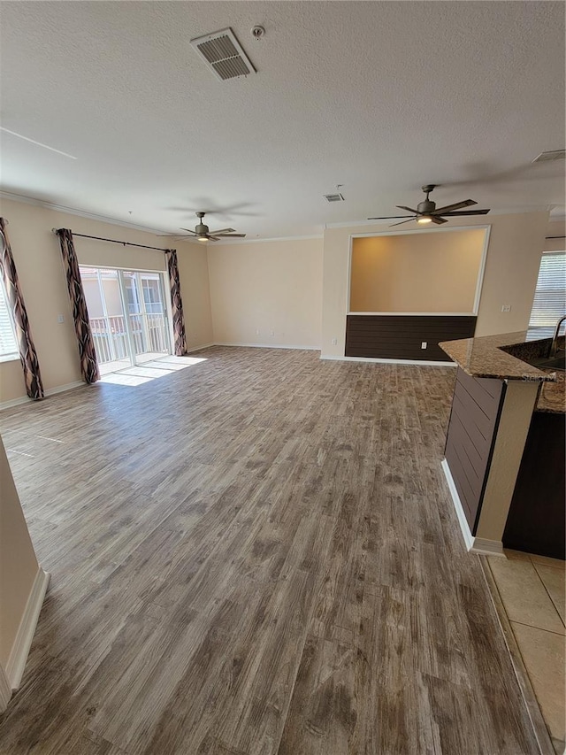 unfurnished living room featuring ceiling fan, hardwood / wood-style floors, and a textured ceiling