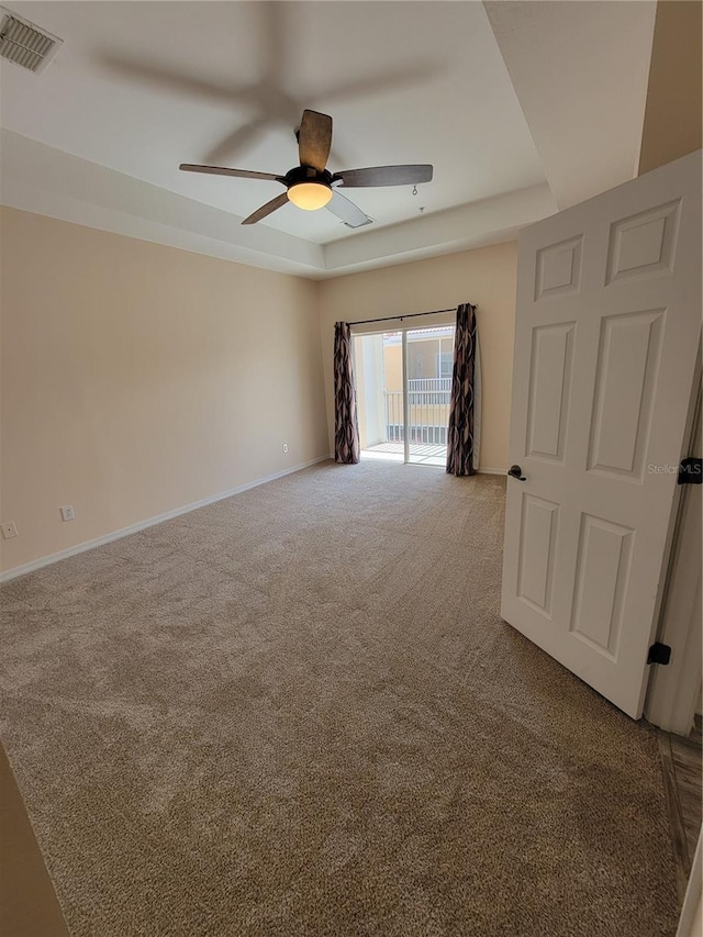 carpeted spare room with ceiling fan and a tray ceiling