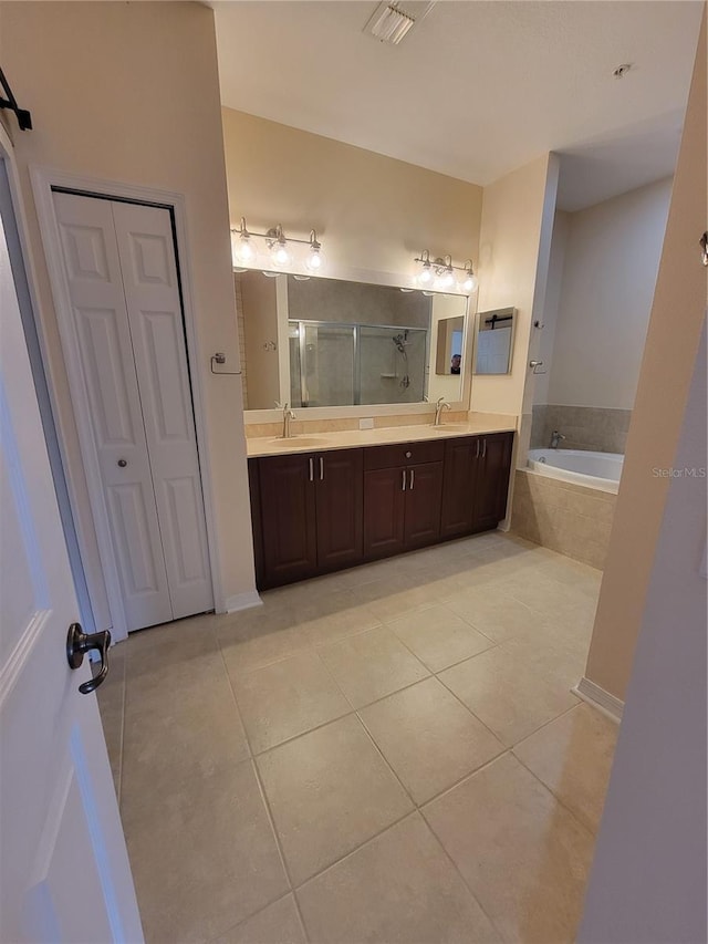 bathroom featuring tiled tub, vanity, and tile patterned floors