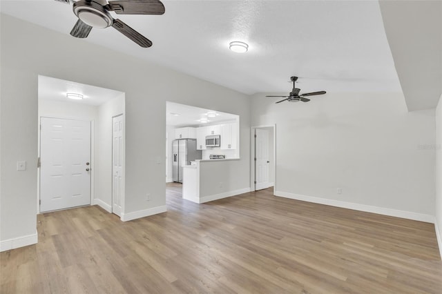 unfurnished living room with ceiling fan, vaulted ceiling, and light hardwood / wood-style flooring