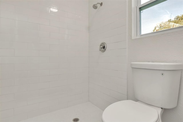 bathroom featuring a tile shower and toilet