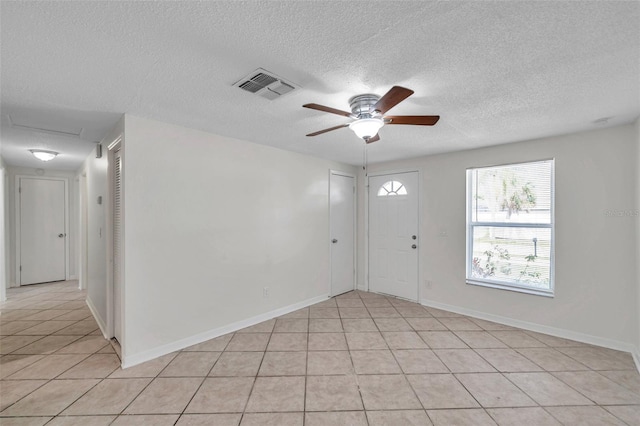 unfurnished room with light tile patterned flooring, ceiling fan, and a textured ceiling