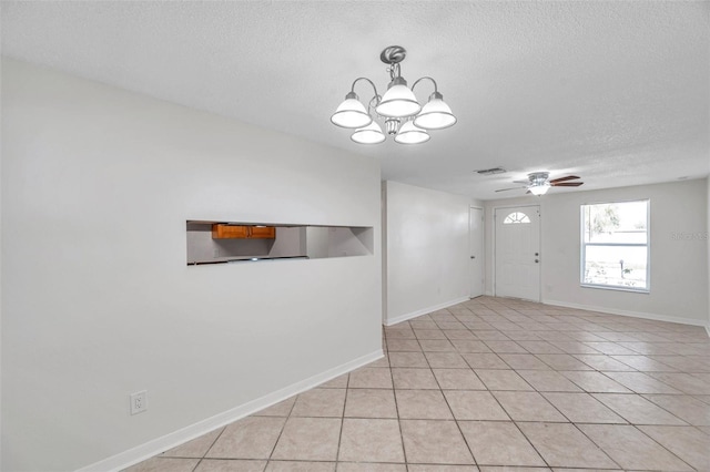 spare room featuring light tile patterned floors, ceiling fan with notable chandelier, and a textured ceiling