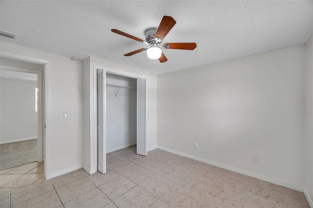 unfurnished bedroom featuring ceiling fan, a closet, a textured ceiling, and light tile patterned flooring