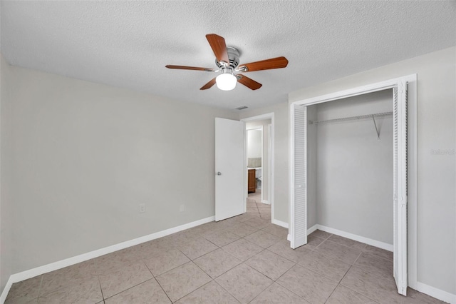 unfurnished bedroom with ceiling fan, a closet, a textured ceiling, and light tile patterned floors