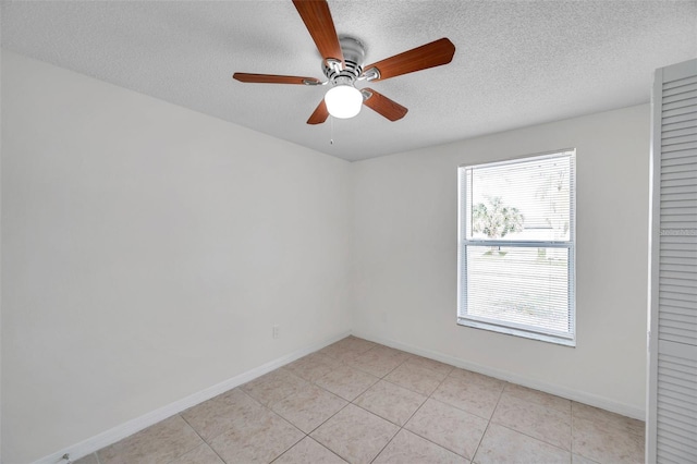 tiled empty room featuring ceiling fan and a textured ceiling