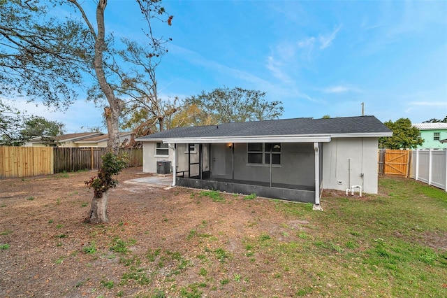 back of house featuring a sunroom, central AC, and a lawn