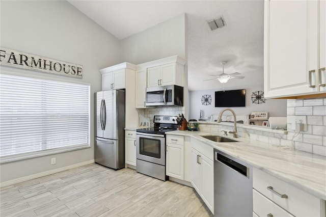 kitchen featuring white cabinetry, sink, light stone countertops, and appliances with stainless steel finishes