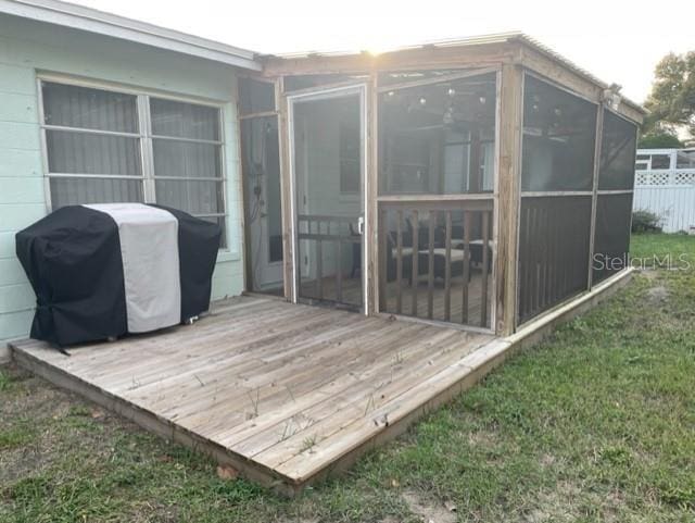 wooden deck with a sunroom and a grill