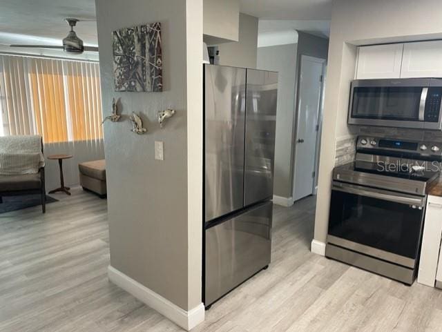 kitchen with stainless steel appliances, white cabinets, and light hardwood / wood-style flooring