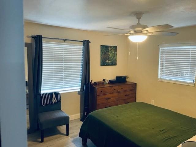 bedroom featuring multiple windows, ceiling fan, and light hardwood / wood-style flooring