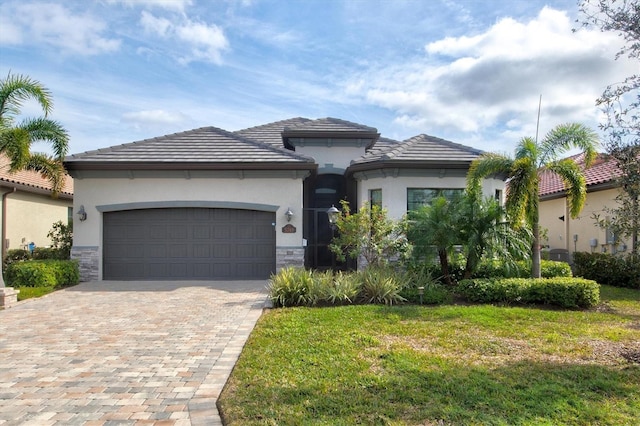 view of front of property with a garage, stone siding, decorative driveway, stucco siding, and a front lawn