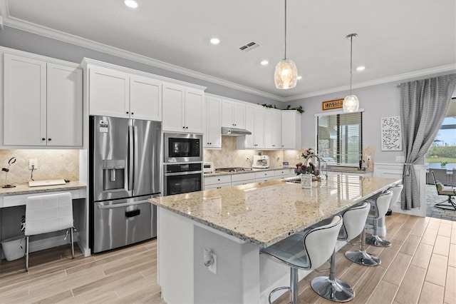 kitchen with stainless steel appliances, visible vents, ornamental molding, a sink, and under cabinet range hood