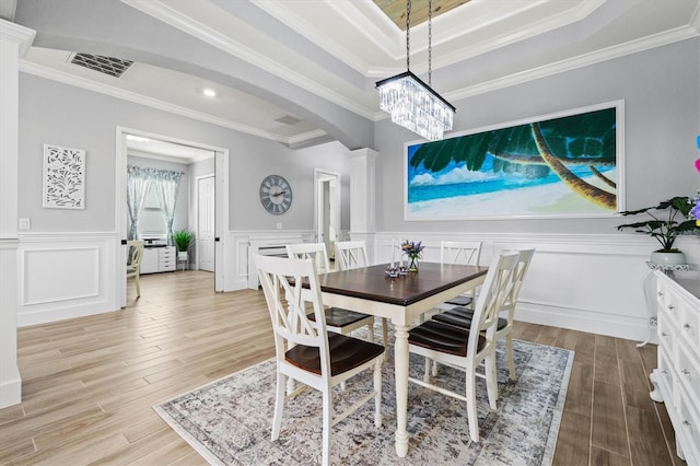 dining room with arched walkways, light wood finished floors, ornamental molding, and visible vents