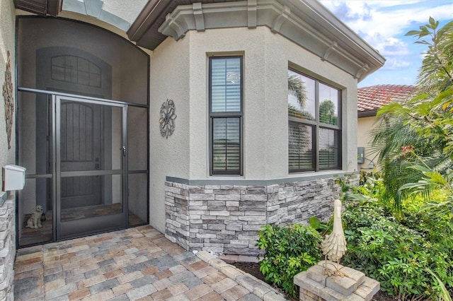 doorway to property with stone siding and stucco siding