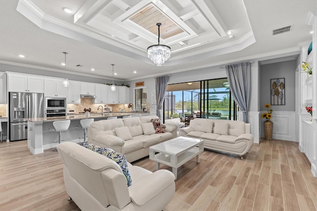 living room with light wood-style flooring, visible vents, and a tray ceiling