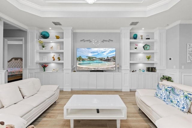 living room with light wood finished floors, a tray ceiling, and built in features