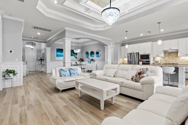 living room with arched walkways, a notable chandelier, visible vents, ornamental molding, and ornate columns