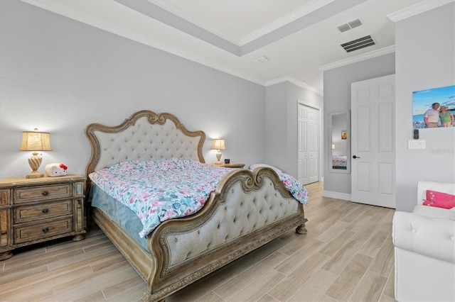 bedroom with light wood finished floors, a closet, visible vents, and crown molding