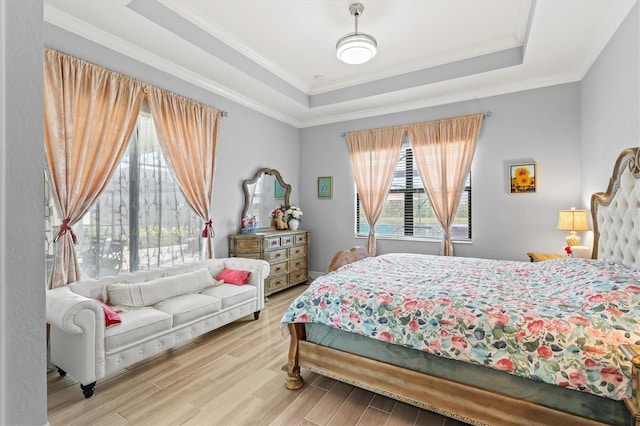 bedroom with wood finished floors, a raised ceiling, and crown molding