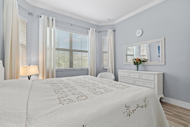 bedroom featuring ornamental molding, multiple windows, wood finished floors, and baseboards