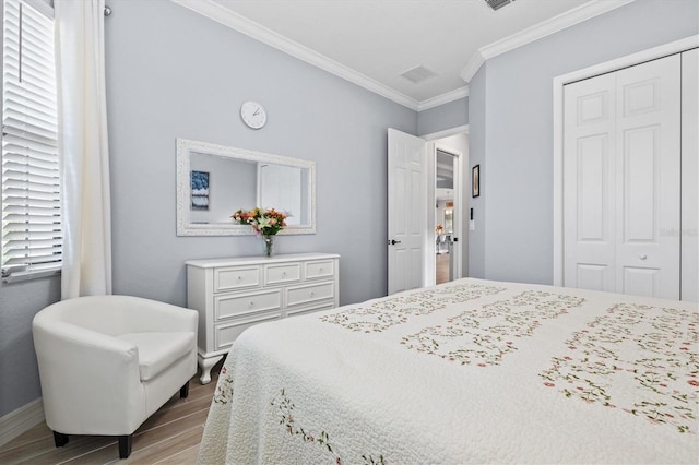 bedroom featuring ornamental molding, a closet, baseboards, and wood finished floors